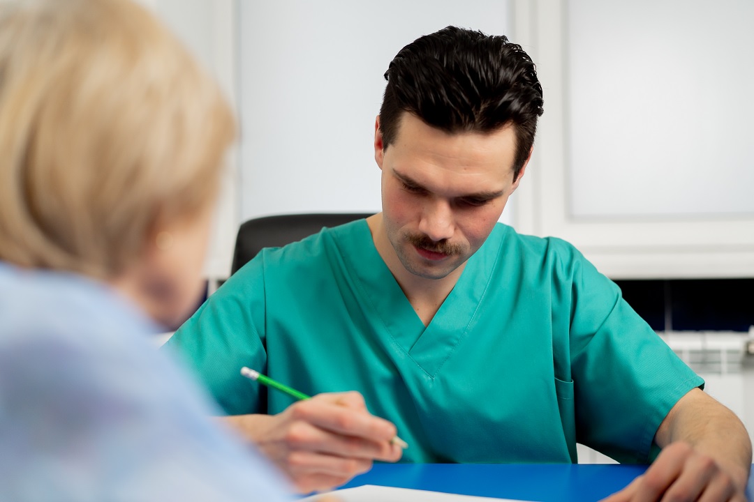 Physical therapist performing manual note-taking during appointment, lowering patient satisfaction